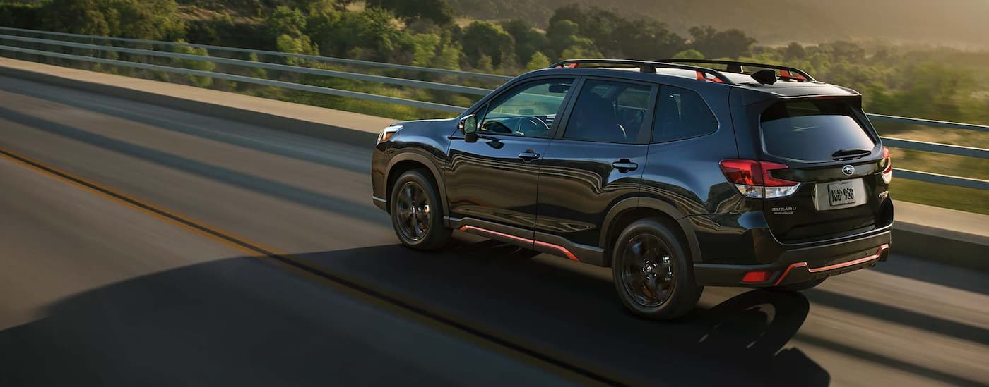 A black 2022 Subaru Forester is shown driving over a bridge.