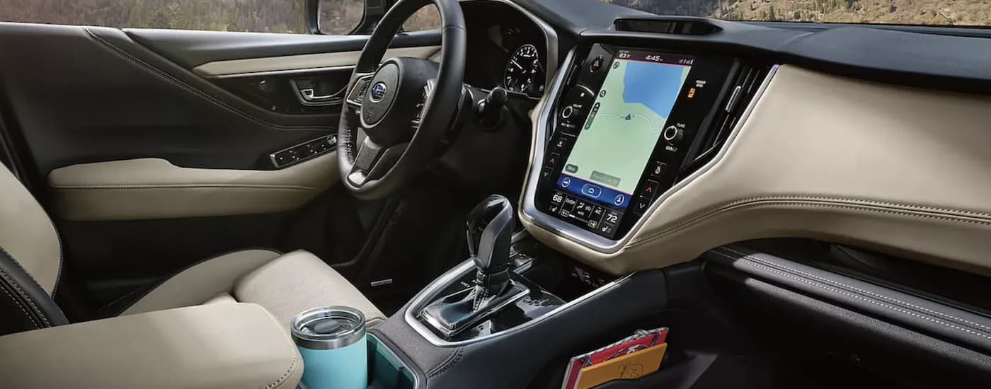 The tan interior of a 2022 Subaru Outback shows the steering wheel and infotainment screen.