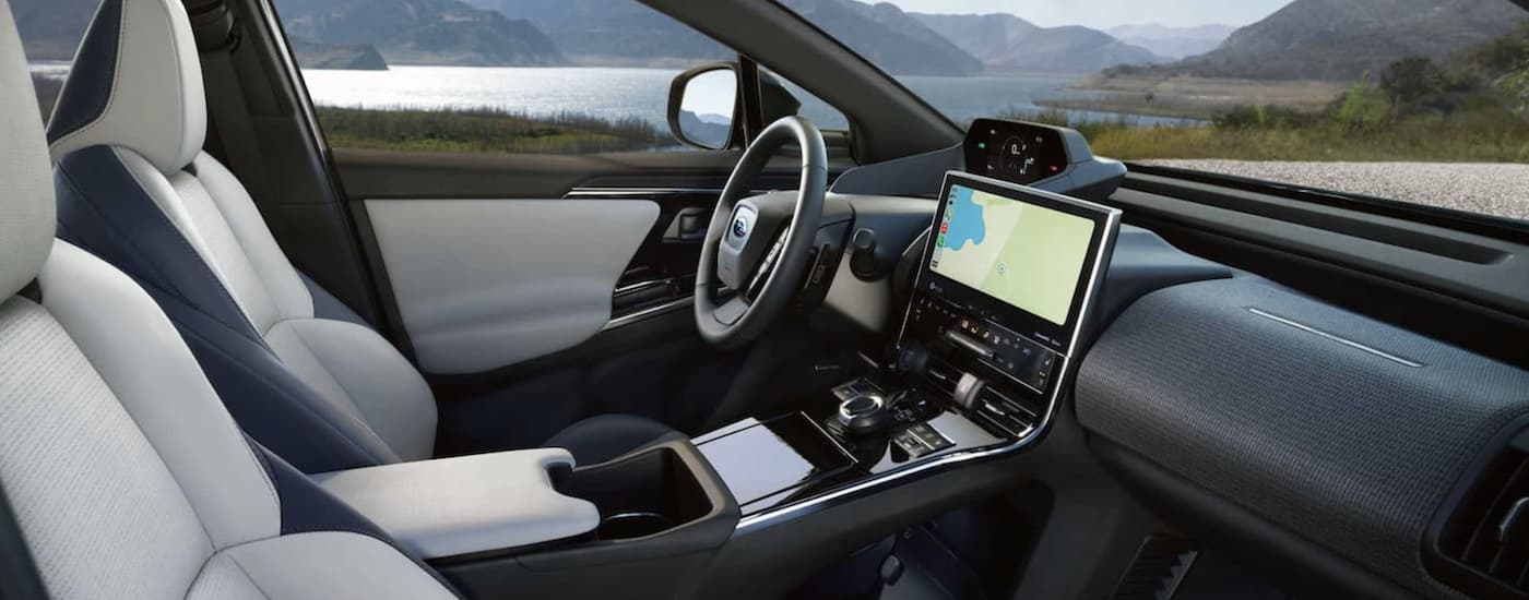 The black and grey interior of a 2023 Subaru Solterra shows the steering wheel and infotainment screen.