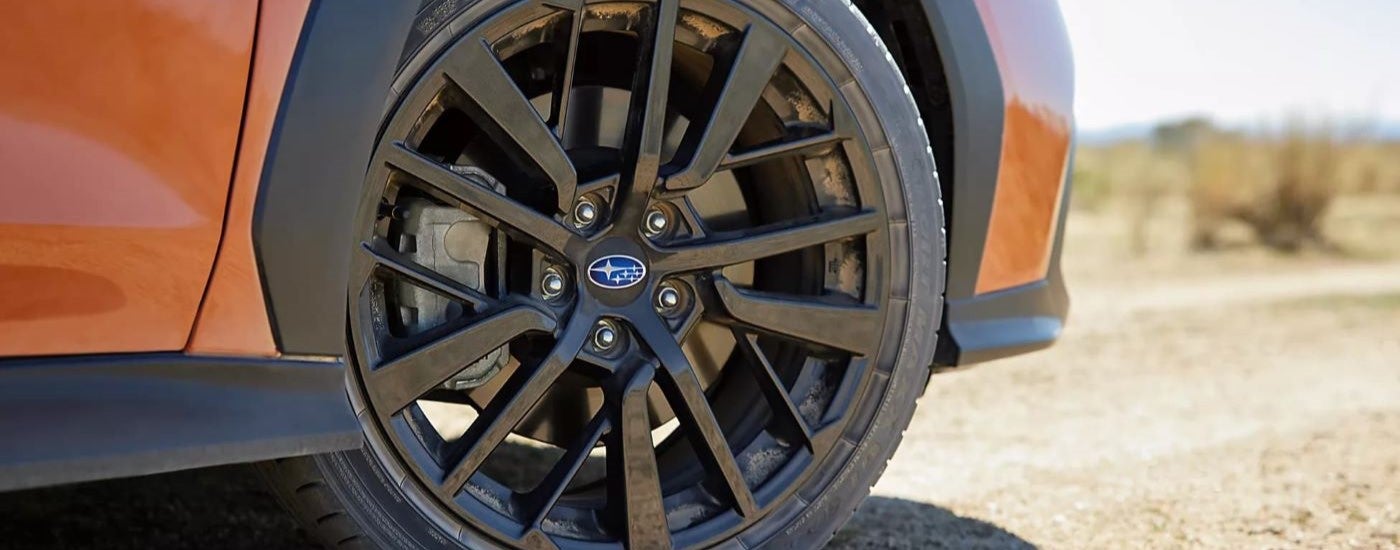 A close up of the black wheel on an orange 2023 Subaru WRX Limited.