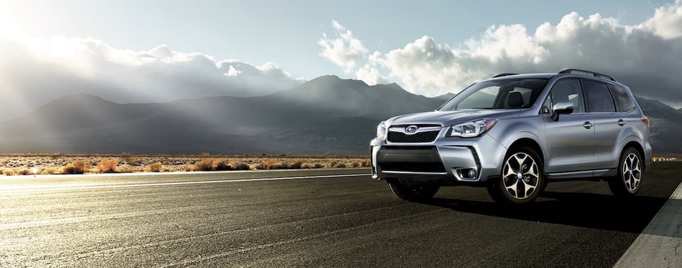 A silver 2015 Certified Pre-Owned Subaru Forester is shown parked on pavement on a cloudy day.