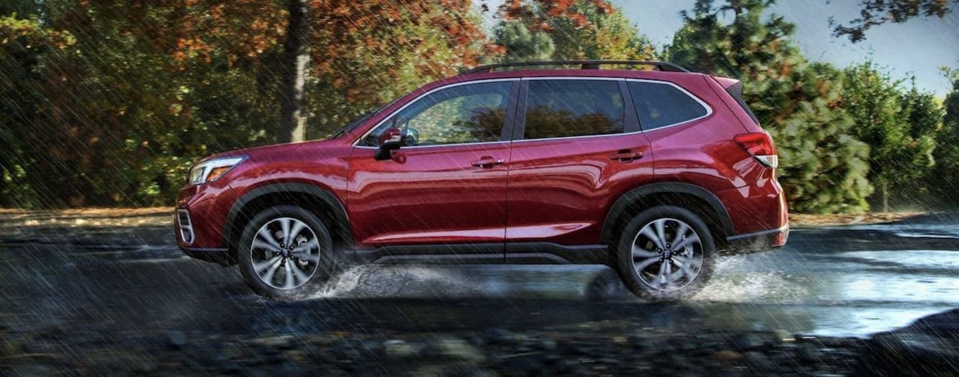 A red 2019 Certified Pre-Owned Subaru Forester Limited is shown from the side driving in the rain.