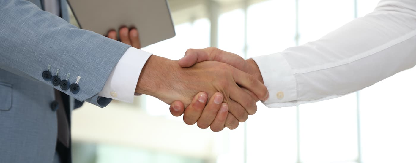 Two people are shown shaking hands at a Charlotte Subaru dealership.