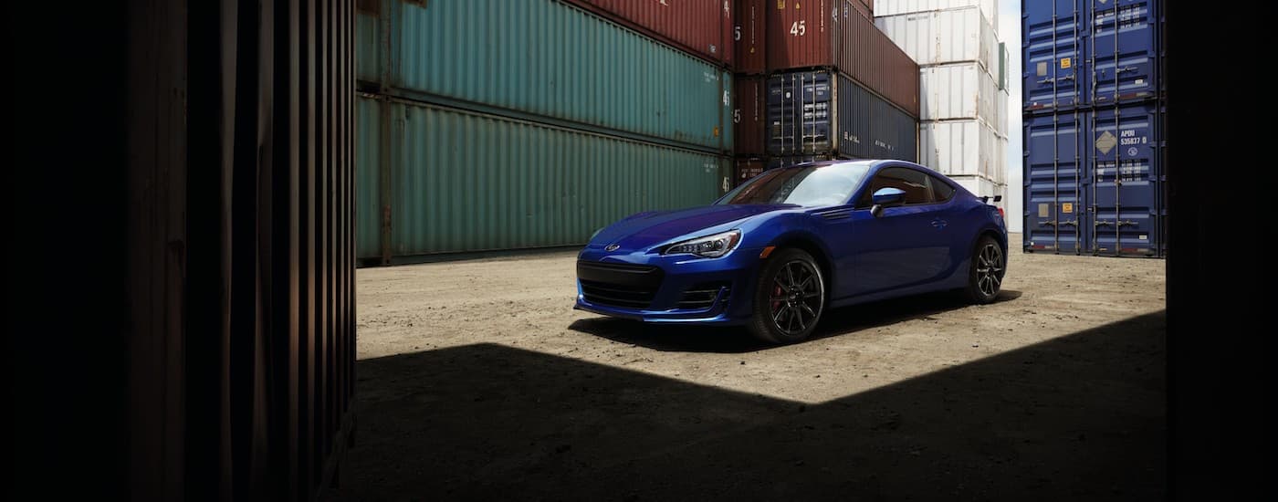 A blue 2017 Subaru BRZ is shown parked near shipping containers.