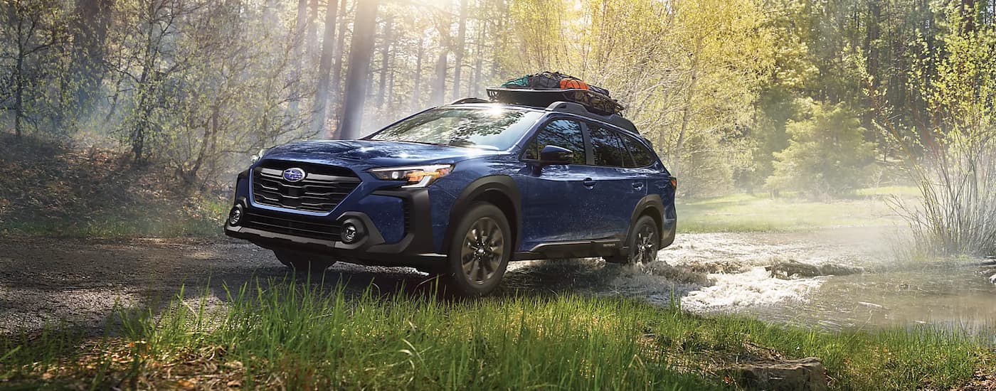 A blue 2023 Subaru Outback Onyx Edition XT is shown on a trail in the woods after visiting a Subaru dealer near Pineville.