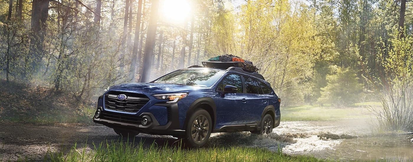 A blue 2024 Subaru Outback in Concord is shown driving off-road.