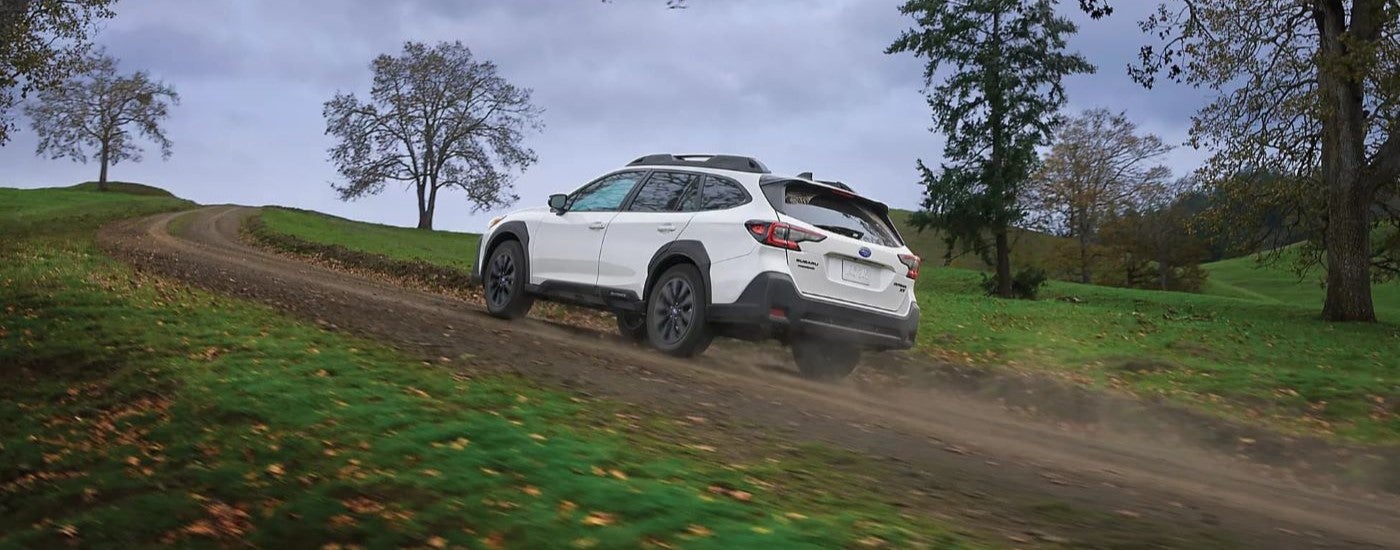 A white 2023 Subaru Outback XT Onyx is shown driving up a trail.