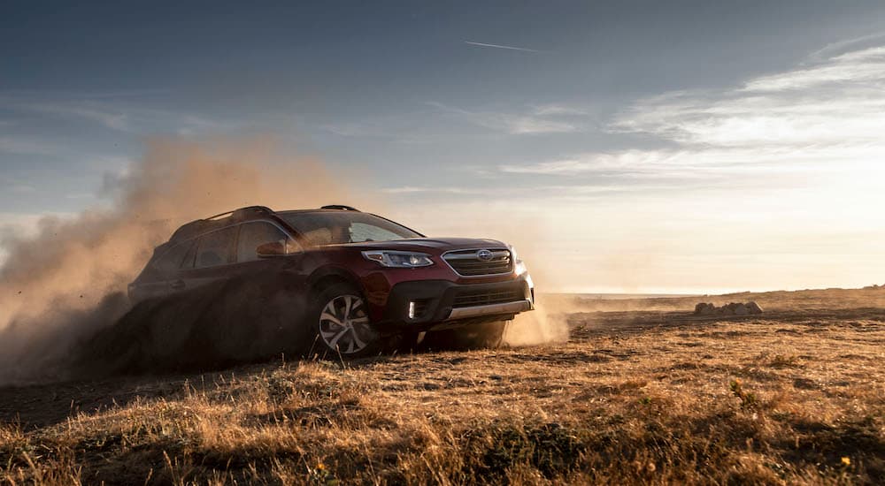 A red 2020 Subaru Outback kicking up dust in a dry field