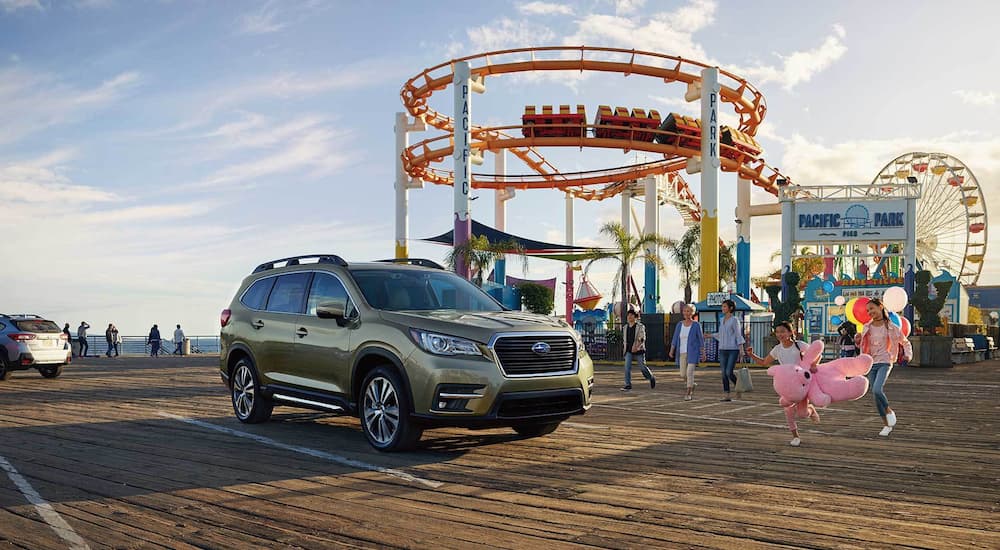 A green 2022 Subaru Ascent Limited parked in front of a carnival.