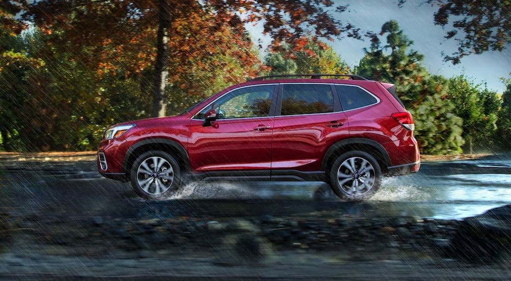 A red 2019 Subaru Forester Touring is shown from the side driving in the rain.
