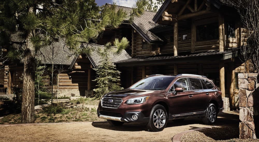 A brown 2016 Subaru Outback is shown parked in front of a cabin.
