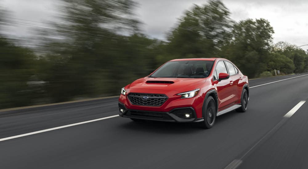 A red 2022 Subaru WRX is shown driving down a highway after leaving a Charlotte used car dealer.