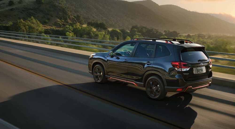 A black 2021 Subaru Forester is shown from the rear leaving a certified pre-owned Subaru dealer in Charlotte.