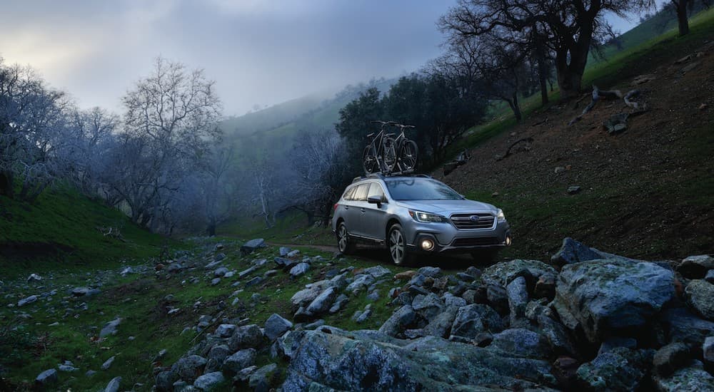 A grey 2018 Subaru Outback is shown on a trail after leaving a certified pre-owned Subaru dealership.