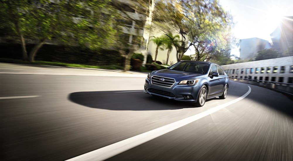 A blue 2017 Subaru Legacy Sport is shown driving on a city street.