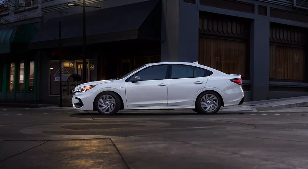 A white 2023 Subaru Legacy is shown on a city street after leaving a Pineville Subaru dealer.