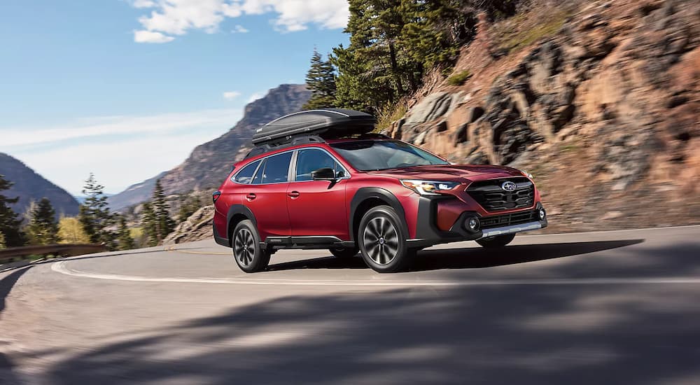A red 2023 Subaru Outback is shown rounding a corner after leaving a Subaru Outback dealer.