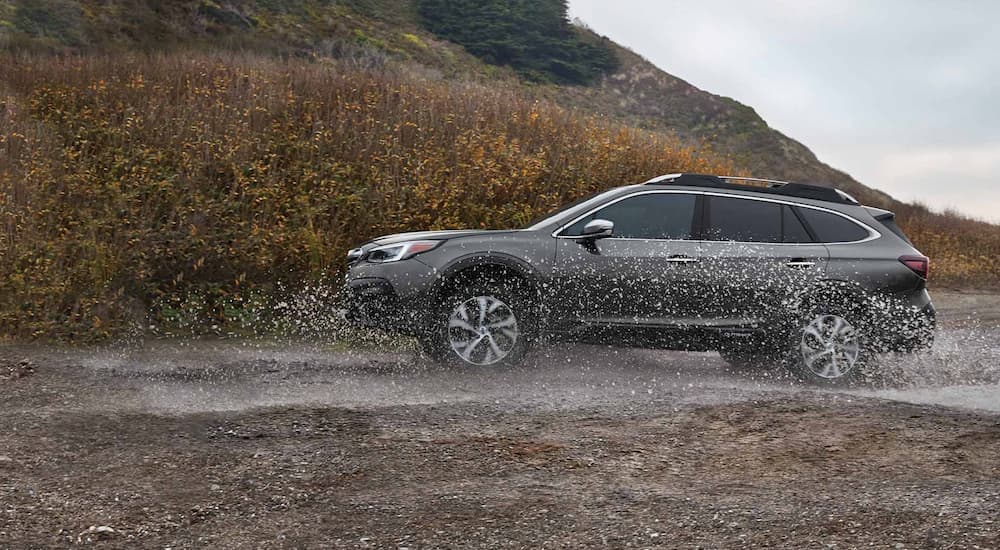 A grey 2021 Subaru Outback is shown from the side driving in the rain.
