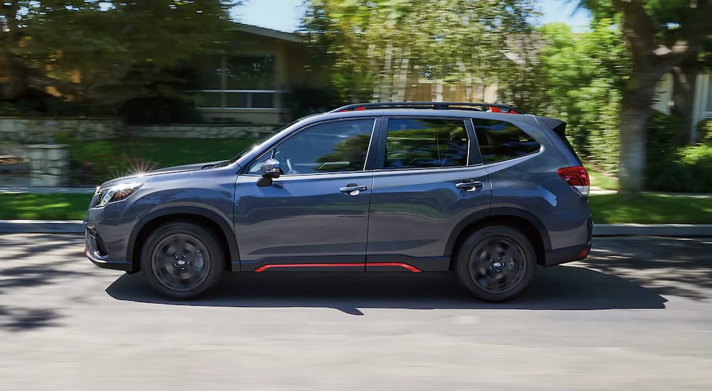 Side view of a black 2023 Subaru Forester Sport driving on a city street.