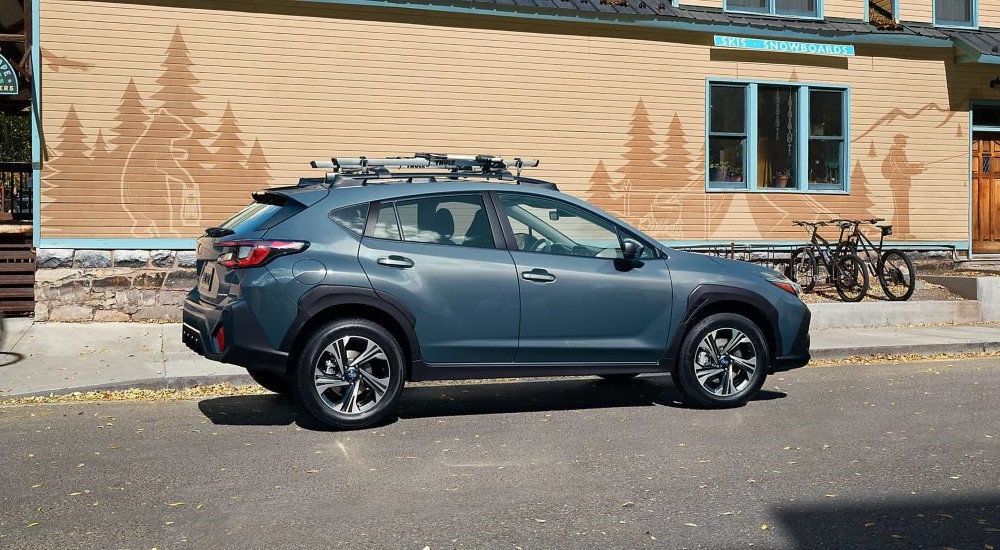 A grey 2024 Subaru Crosstrek parked in front of a brick storefront