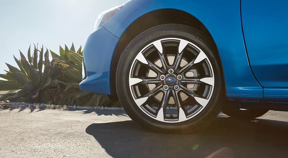 A close up of the front tire of a blue 2023 Subaru Impreza 