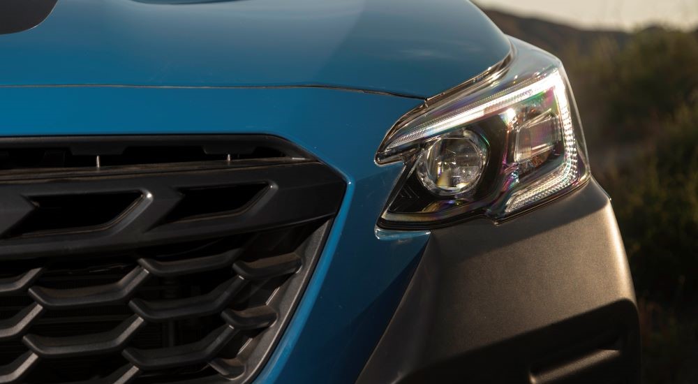 A close up shows the driver side headlight on a blue 2022 Subaru Outback Wilderness after leaving a Subaru dealer near you.