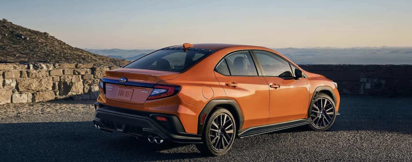An orange 2022 Subaru WRX is shown from the rear overlooking a mountain view.