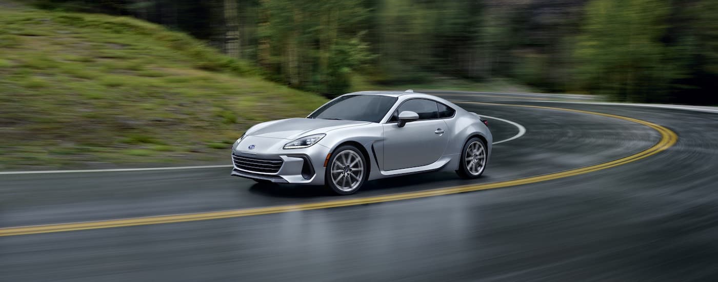 A silver 2023 Subaru BRZ rounding the corner on a wet road.