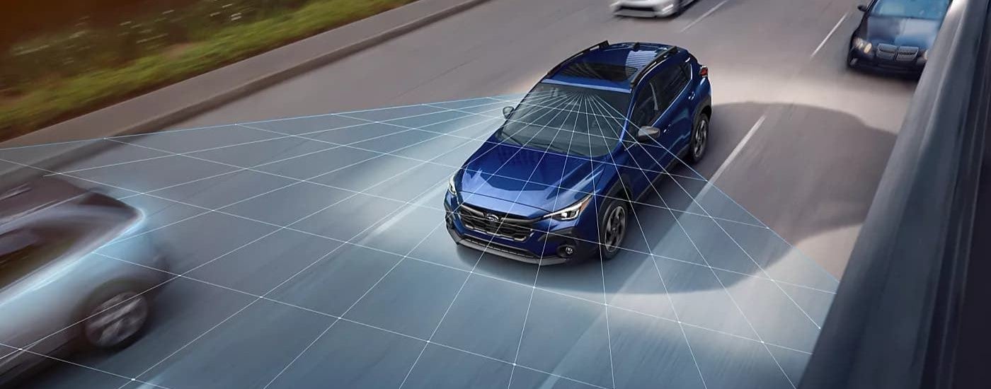 A blue 2024 Subaru Crosstrek driving in traffic with simulated sensor lines projected ahead of it