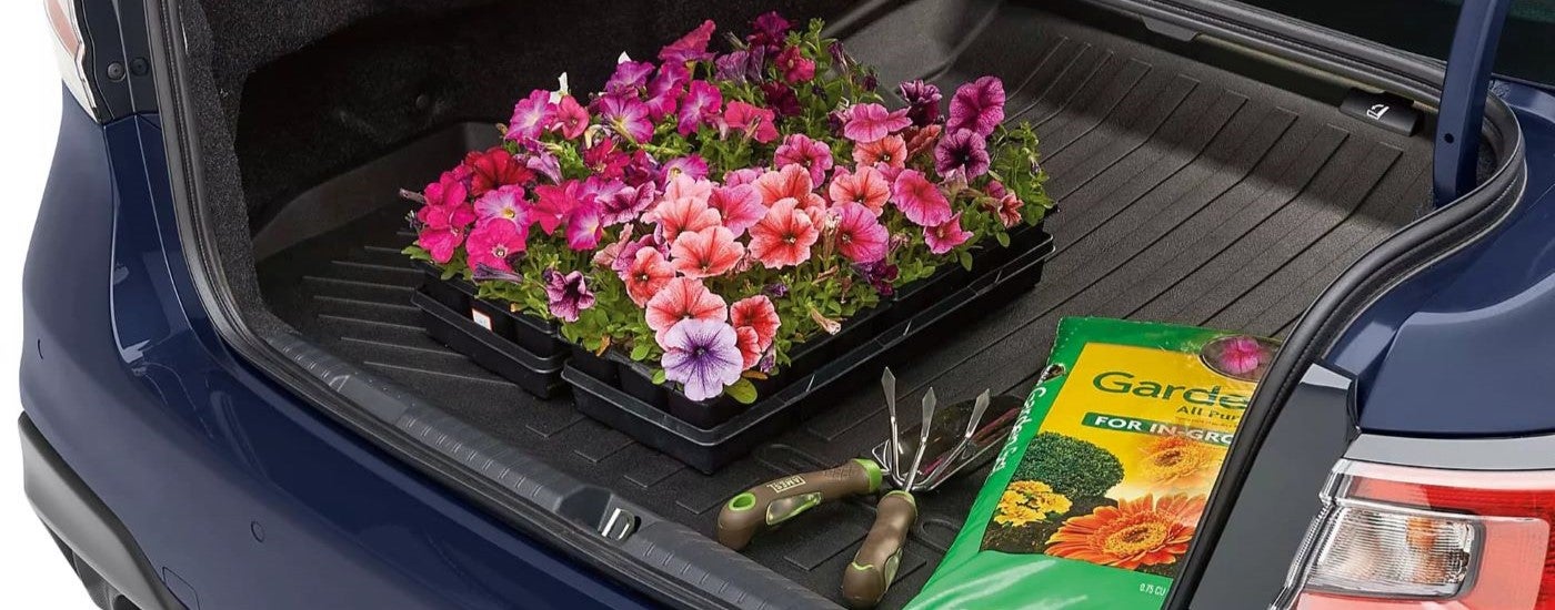 Flowers and potting soil sitting on all-weather floor mats in the trunk of a 2024 Subaru Legacy.