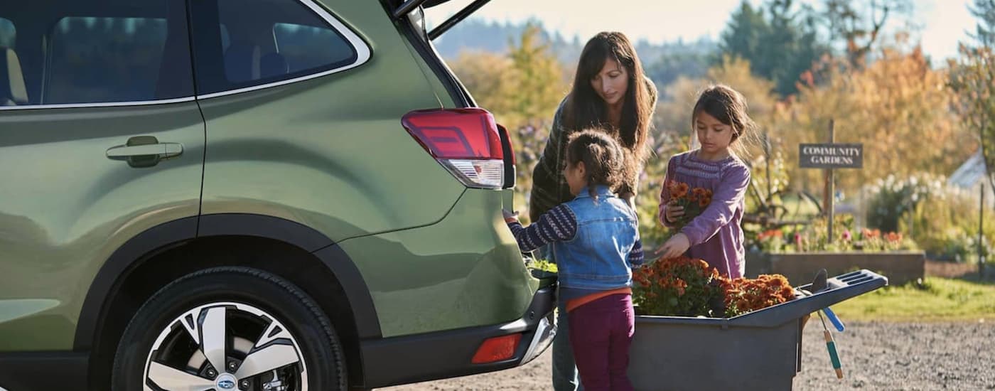 A family is shown putting flowers in the rear cargo space of a green 2021 Subaru Forester.