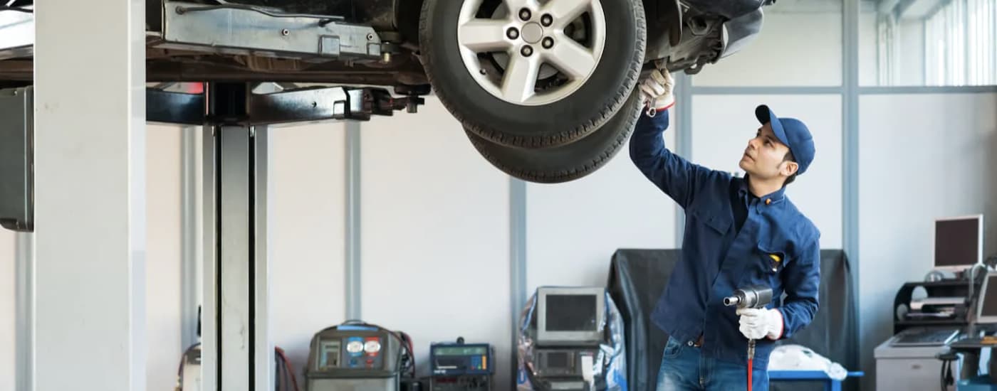 A mechanic is shown working on a vehicle at a Certified Pre-Owned Subaru dealership.