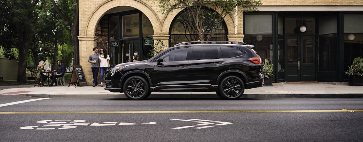 A black 2022 Subaru Ascent is shown from the side parked in front of a building.