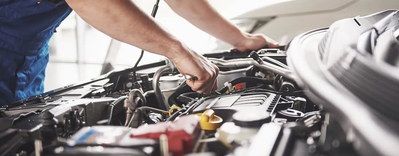 A mechanic is working under the hood of a car.