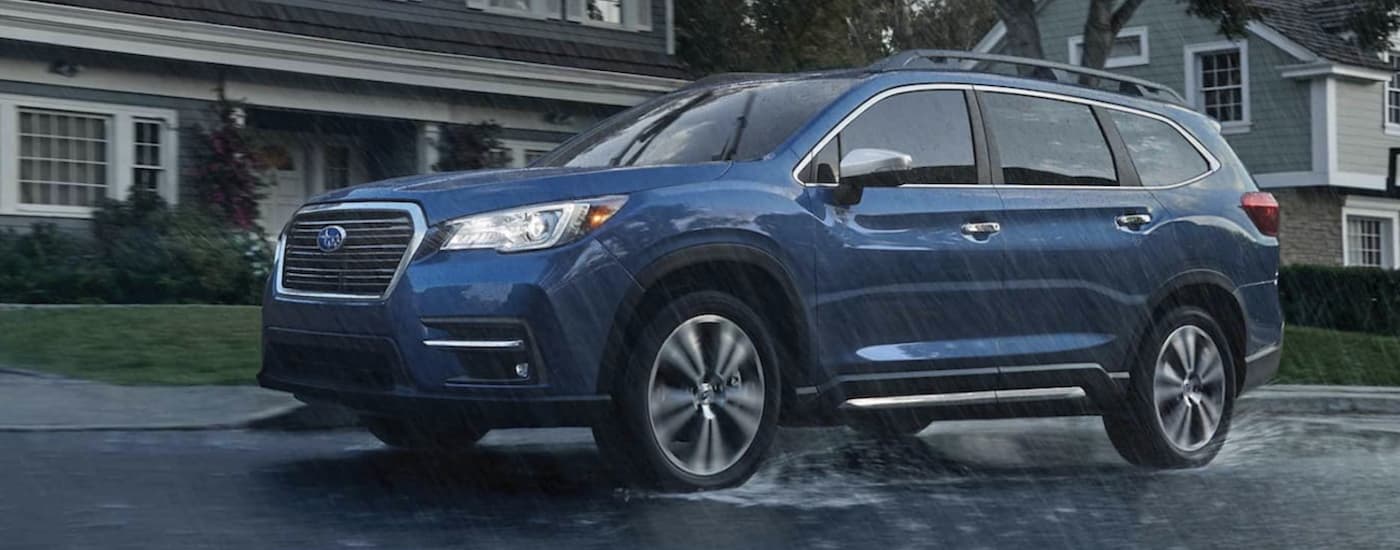 A blue 2022 Subaru Ascent Touring is shown driving in the rain after leaving a Subaru Ascent dealership.