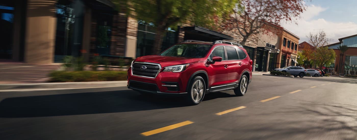 A popular Subaru Ascent for sale, a red 2020 Subaru Ascent, is shown driving on a city street.