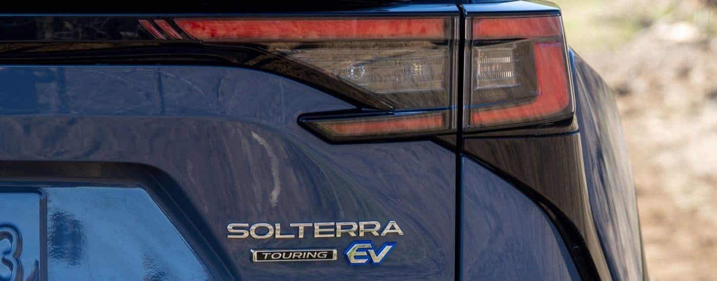 A close up shows the rear badging and passenger side taillight on a blue 2023 Subaru Solterra Touring. 