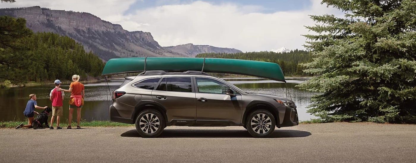 A grey 2024 Subaru Outback is shown next to a lake.