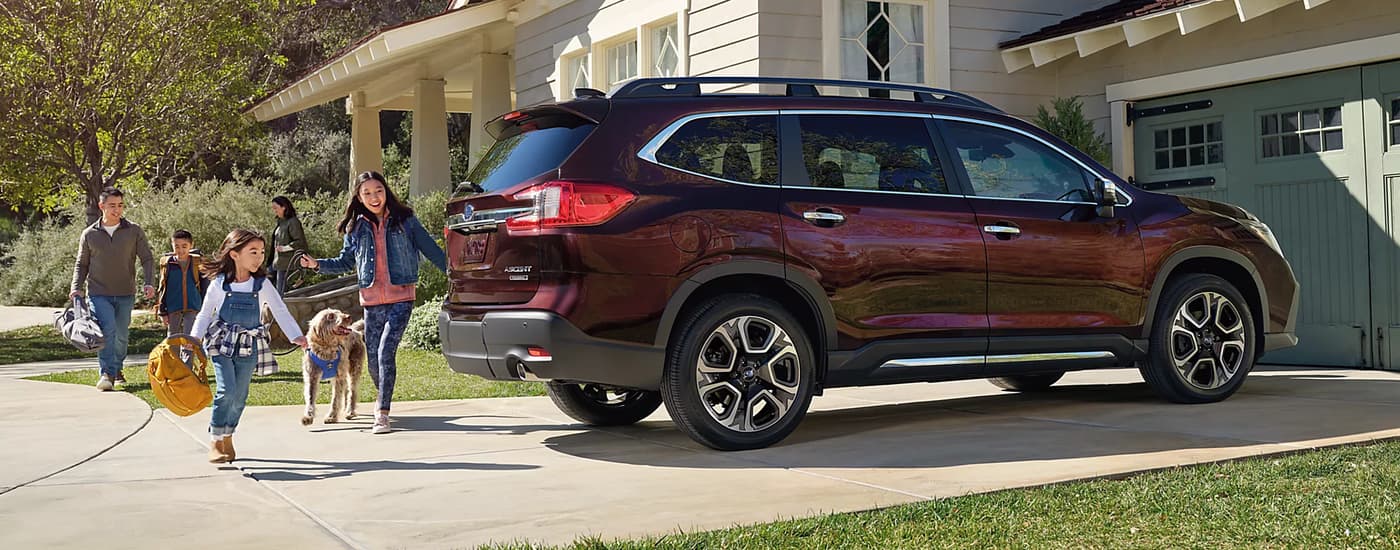 A maroon 2023 Subaru Ascent Touring is shown from the side parked in a driveway.