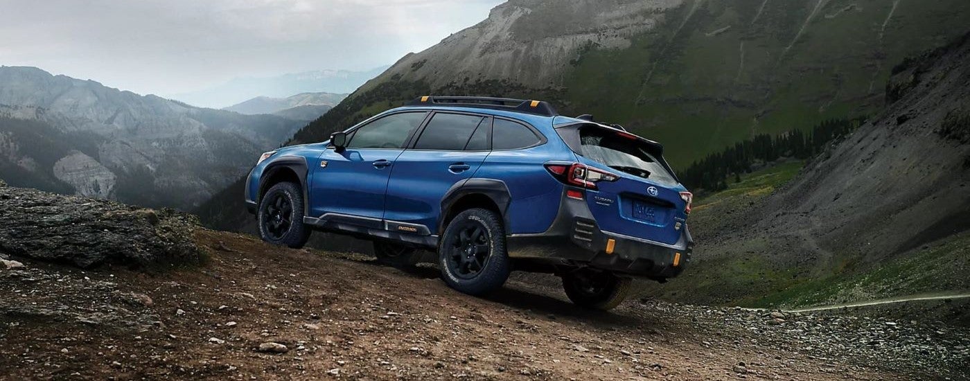 A blue 2023 Subaru Outback Wilderness is shown parked on a mountain path.